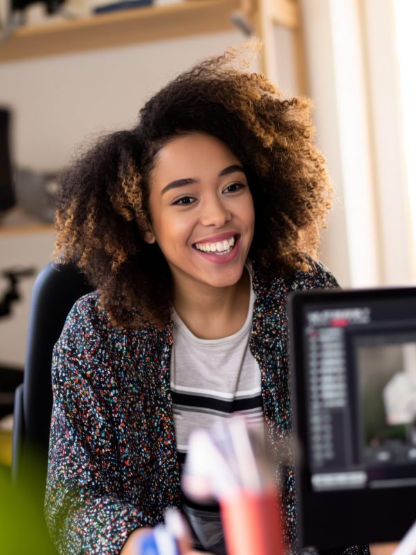 A streamer vlogger woman wearing headphones sits in front of a computer, engrossed in her work.